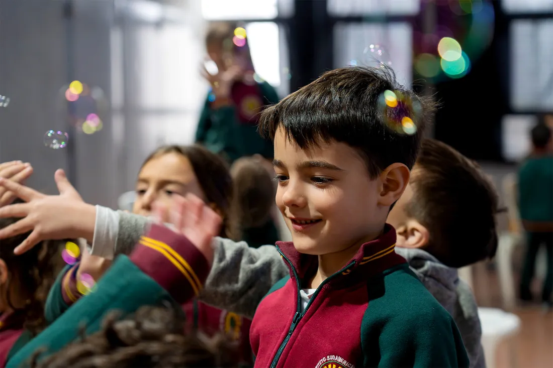 Niño del Jardín de Infantes del IESM riendo entre burbujas de jabón